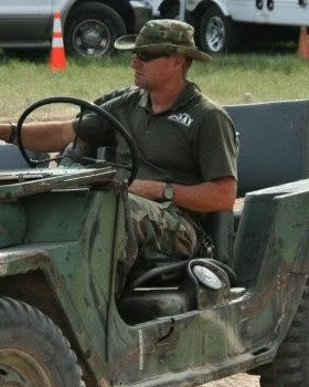 Dewayne Convirs driving a military jeep at a paintball event